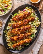 Air Fried Nutty Thai Chicken Skewers 

No need to turn on the oven for these delicious nutty Thai chicken skewers. They cook up quickly in the air fryer with a 5-ingredient nutty-spicy sauce! 
Serve over Asian slaw for a complete meal that is healthy and satisfying. 
~
Ingredients 
~
1 lb. boneless/skinless chicken breast, cubed
3 tbsp creamy natural peanut butter (or any nut butter)
1/4 cup warm water 
2 tbsp coconut aminos 
1 tbsp chili garlic sauce 
1 tbsp honey
2 tbsp chopped roasted peanuts or cashews. 
~
Directions 
~
Soak bamboo skewers in water for 3 minutes. Blot skewers dry. Set aside. 
~
Whisk together peanut butter, water, coconut aminos, honey and chili garlic sauce in a medium bowl until smooth. Add cubed chicken and stir well to coat. Reserve half of the sauce for serving. 
~
Spray basket of air fryer with cooking oil. Slide chicken onto skewers. Place into basket leaving space in between. Air fry for 14 minutes. 
~
Serve chicken skewers hot over rice or slaw topped with remaining sauce. Garnish with chopped nuts.